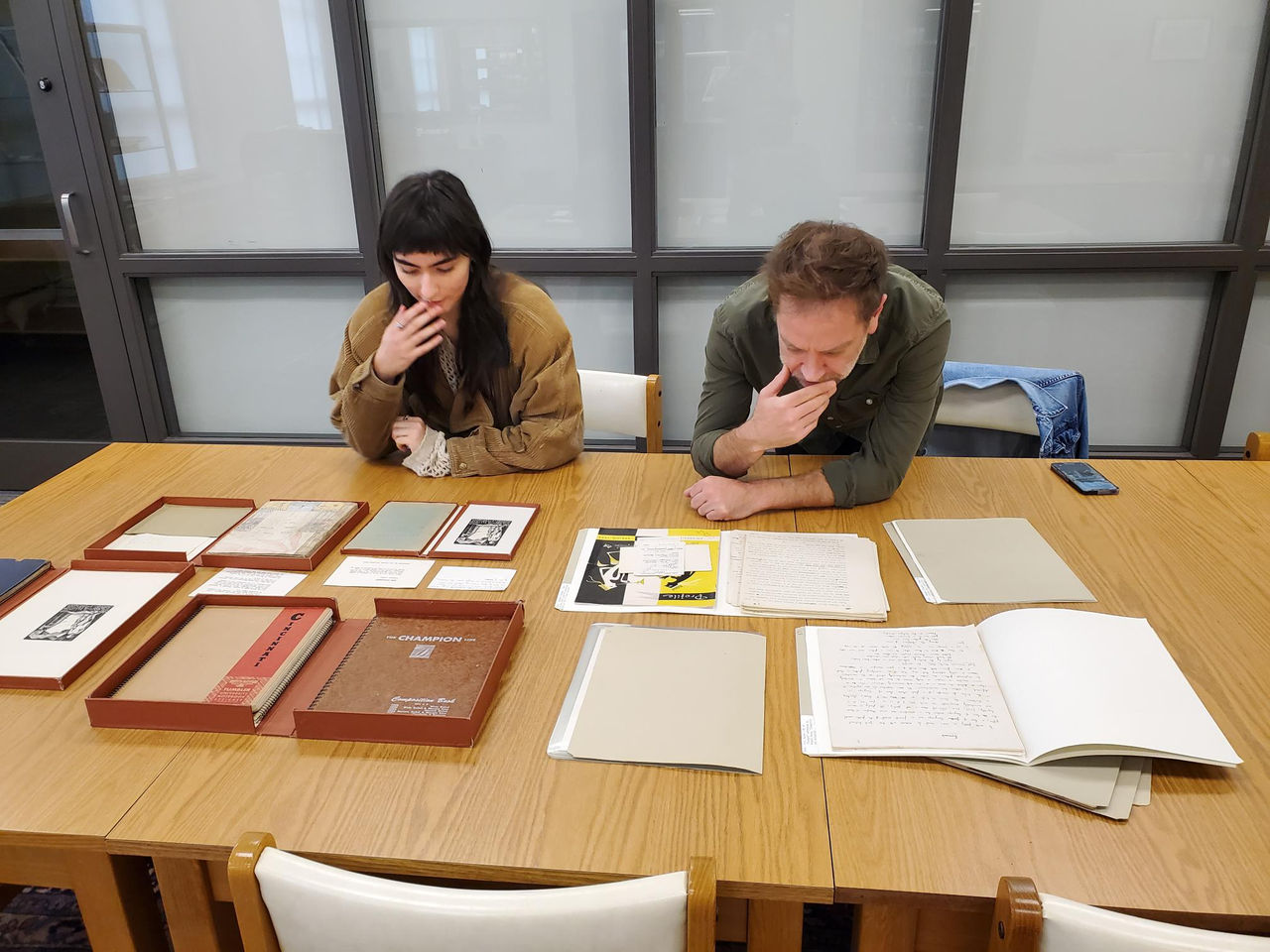 Two people in a library looking at books and folders